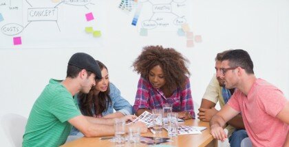 Creative team brainstorming over contact sheets in office with whiteboard