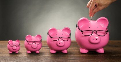 Person Hand Inserting Coin In Piggybank